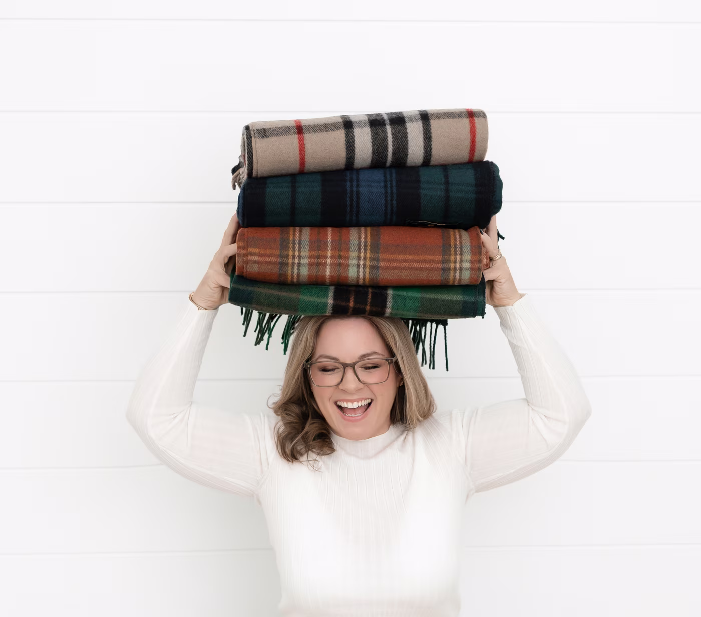Laura McBride, Ajax REALTOR®, laughing while balancing a stack of folded wool blankets