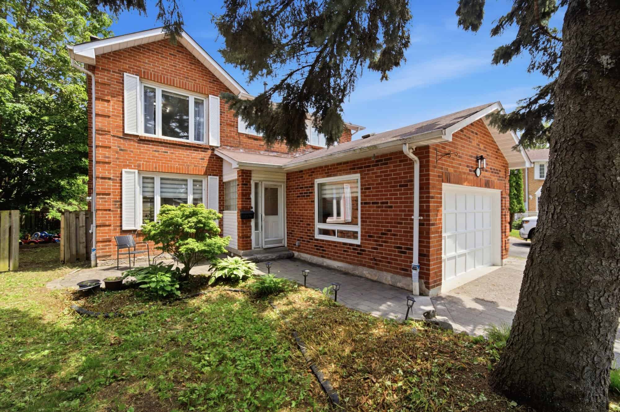 Daytime exterior of 13 Flowers Crescent, South Ajax, a two-storey red-brick detached home with a converted garage main-floor bedroom suite, listed by Laura McBride, Ajax REALTOR®