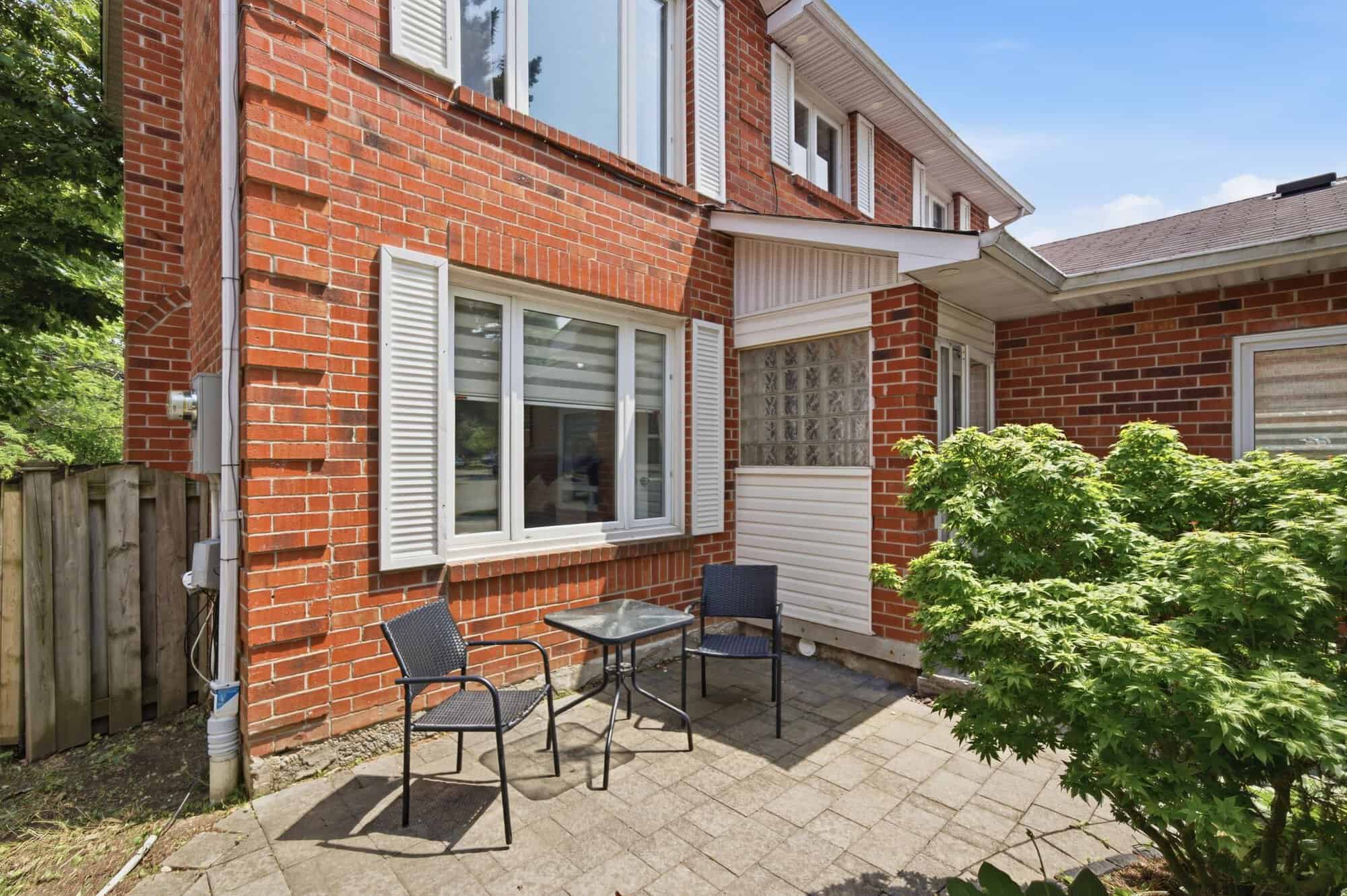 Small paved patio beside the front entrance of 13 Flowers Crescent, South Ajax, with outdoor seating and mature landscaping