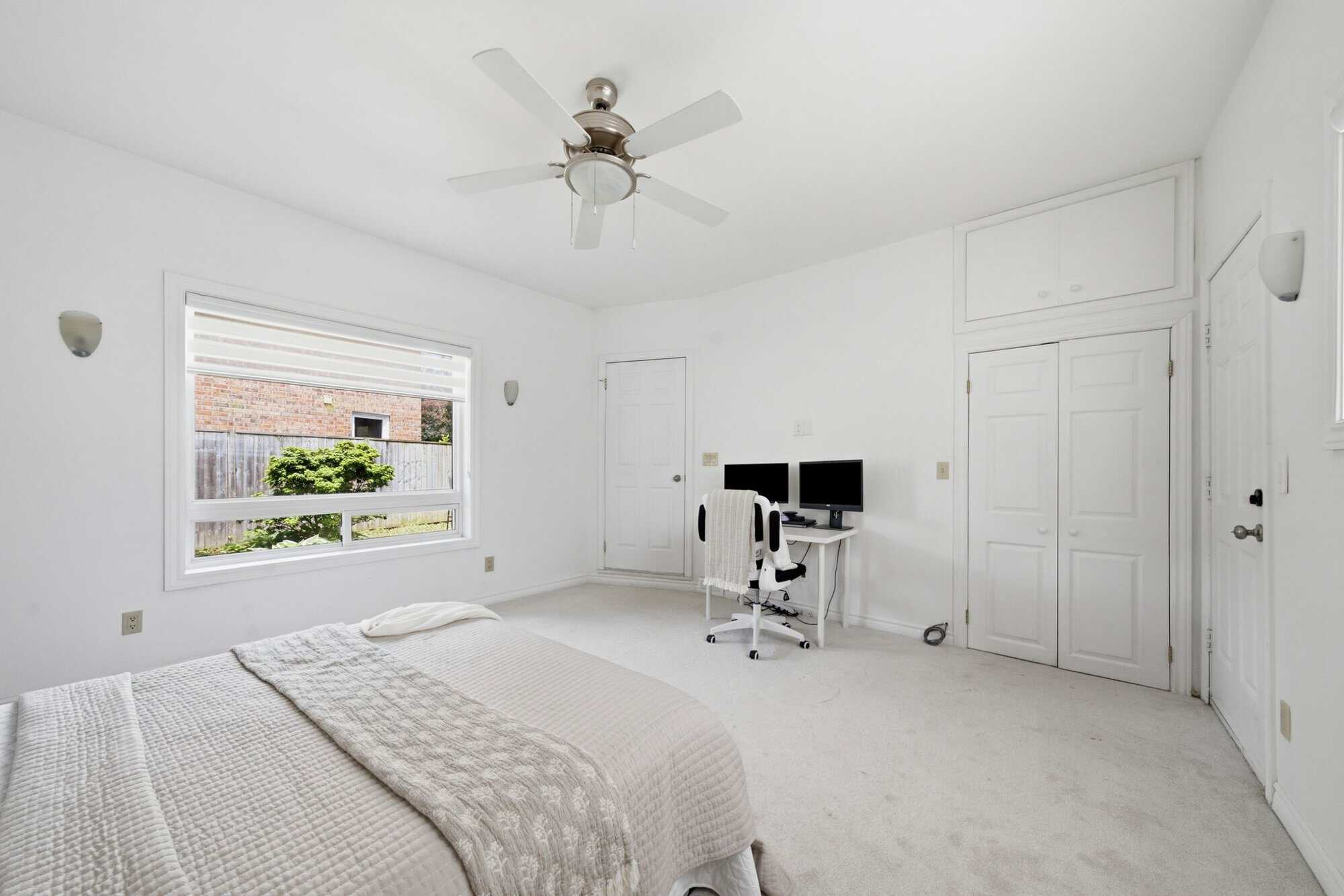 Main-floor bedroom suite at 13 Flowers Crescent, South Ajax, with a large window, built-in storage and exterior door