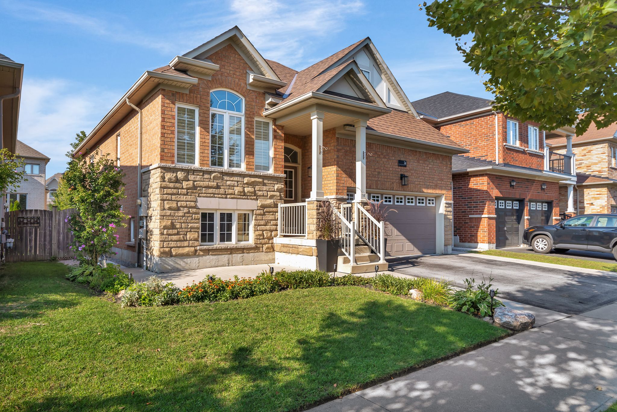 Exterior of 14 Sleepy Hollow Place, Whitby, a brick and stone bungalow with a covered porch and double garage, sold by Laura McBride, Ajax REALTOR® with Revel Realty