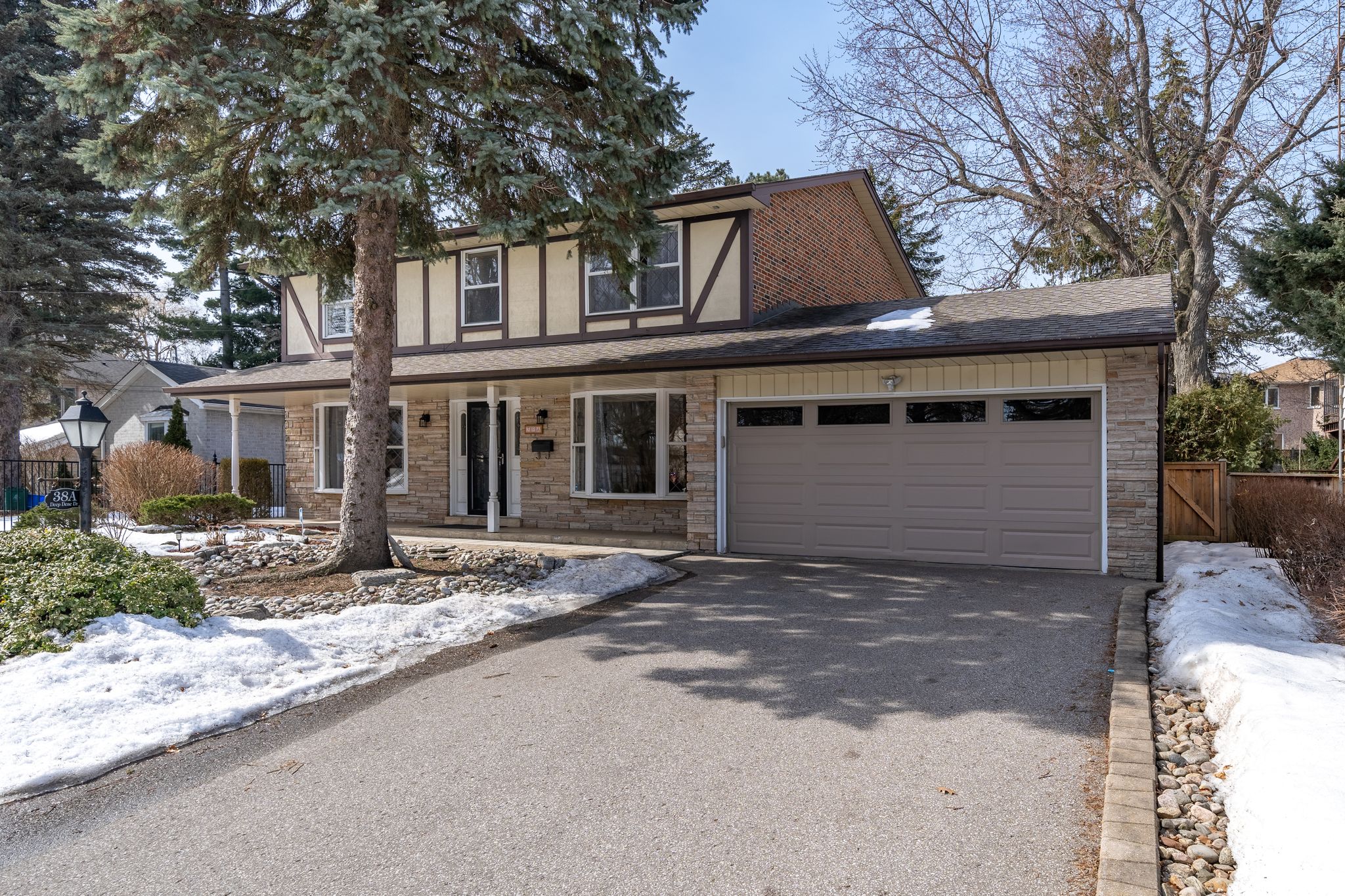 Exterior of 38A Deep Dene Dr, Highland Creek Village, a brick and stone Tudor-style detached home with a double garage, sold by Laura McBride, Ajax REALTOR® with Revel Realty