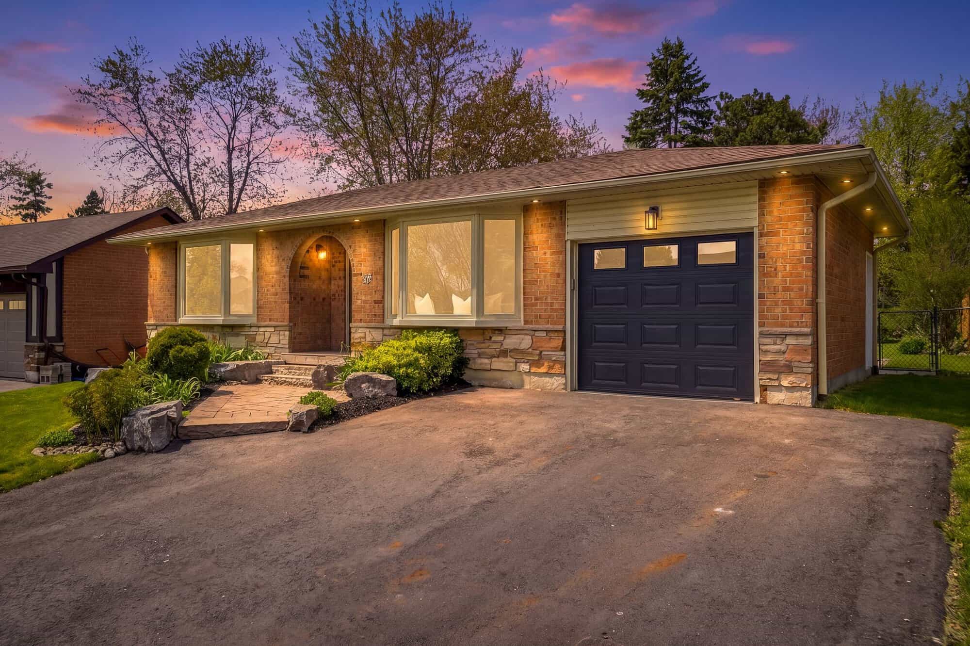 Exterior of 39 Anstead Crescent, South Ajax, at dusk, a brick bungalow with landscaped gardens and a wide driveway, listed by Laura McBride, Ajax REALTOR®