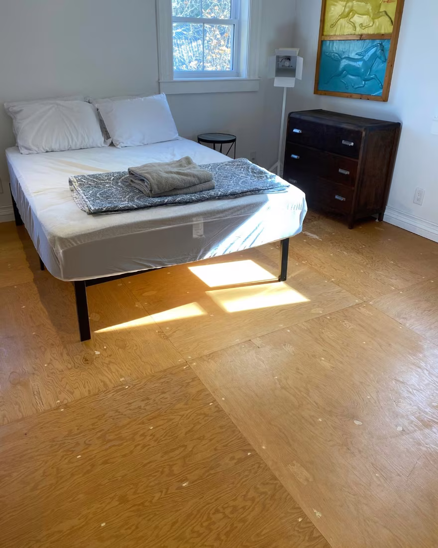 Primary bedroom before staging, with bare floors and minimal, unstyled furnishings