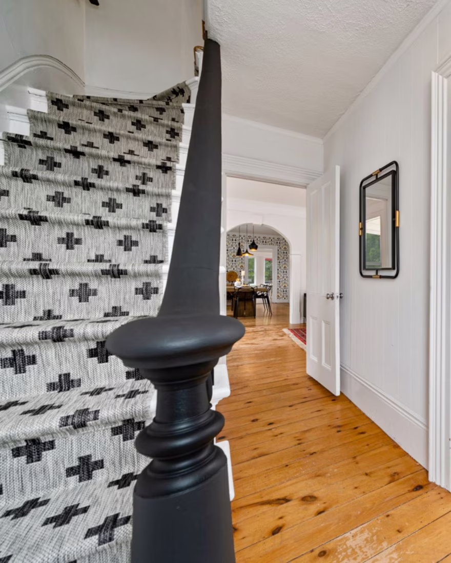 Staircase after staging, with a bold black banister and a modern patterned runner