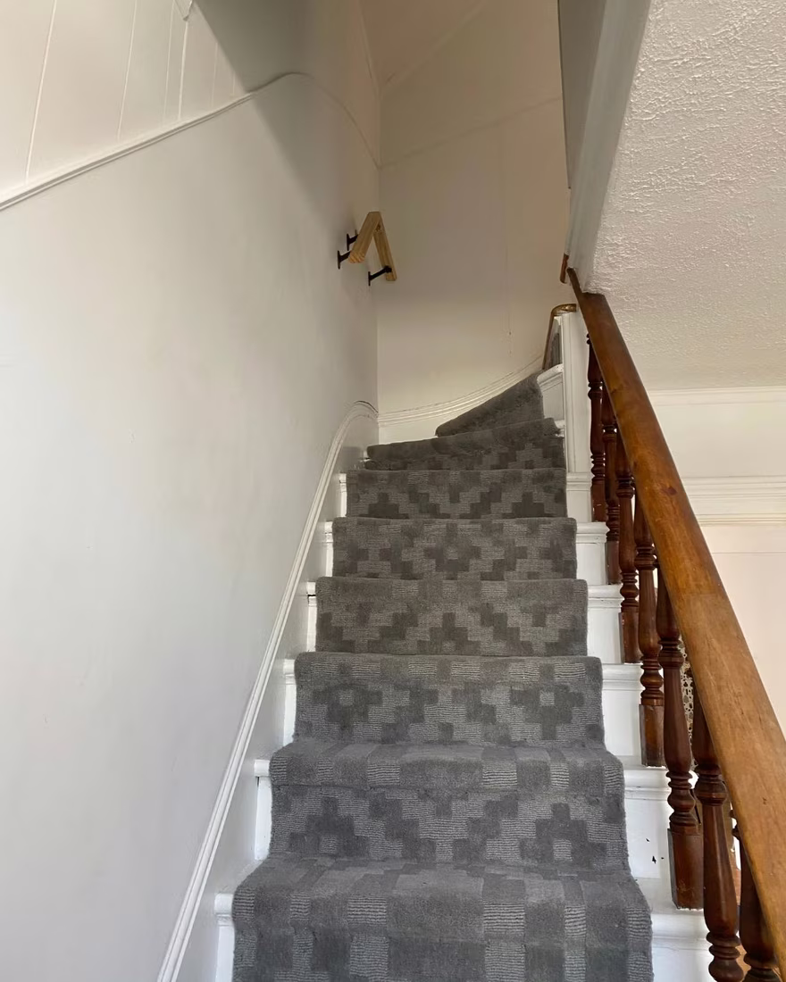 Staircase before staging, with an outdated banister and a plain runner