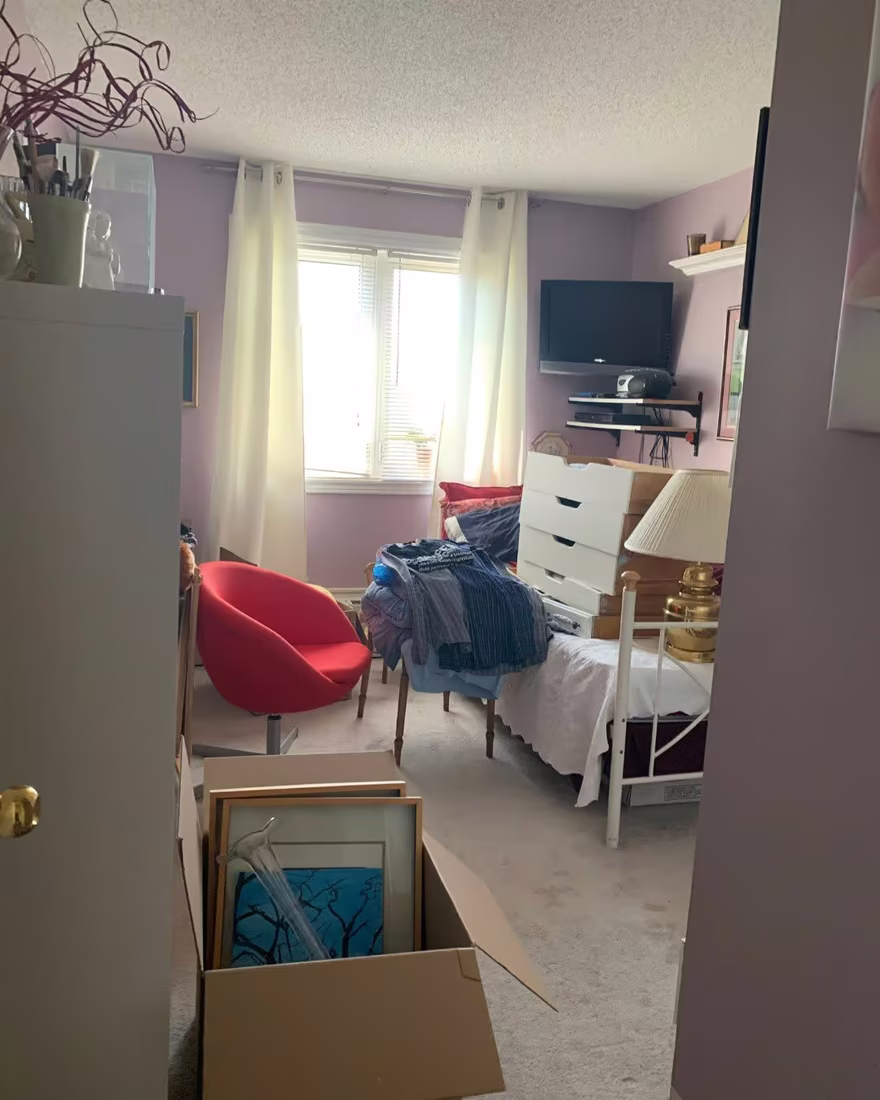 Cluttered storage room with open boxes and a spare chair, before staging