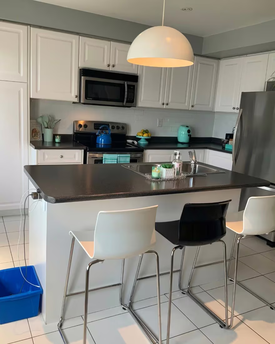 Kitchen island before staging, mismatched kettle and canisters, recycling bin visible